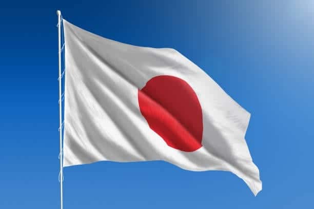 The National flag of Japan blowing in the wind in front of a clear blue sky